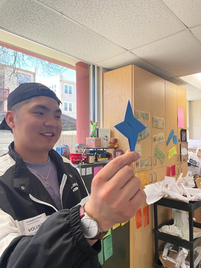 Student holding paper craft and smiling.