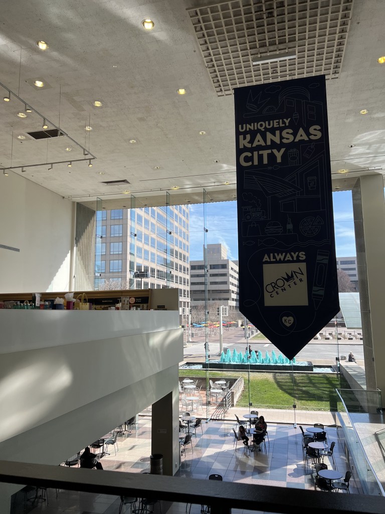 Image of interior of Crown Center shopping center with blue fountains pictured and a banner reading "Uniquely Kansas City"
