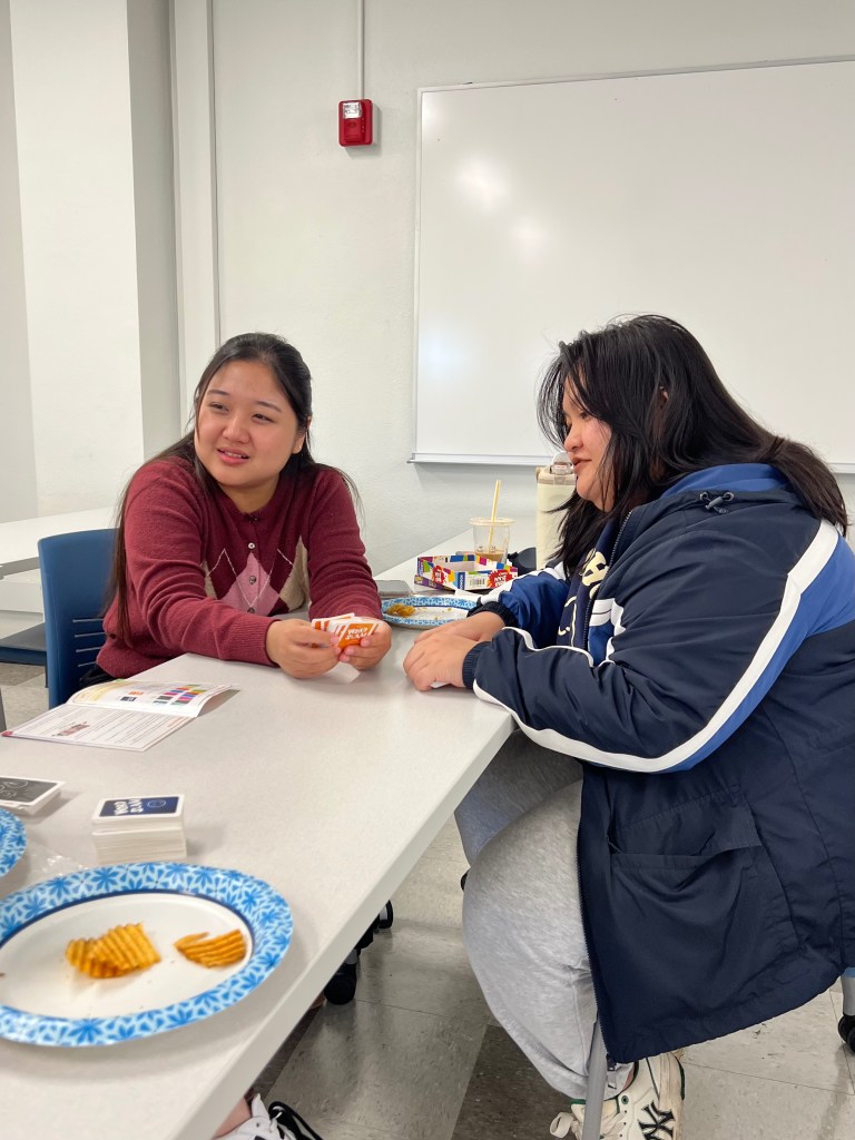 Two students holding game cards and smiling.